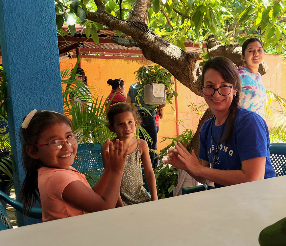 woman playing hand games with young girls