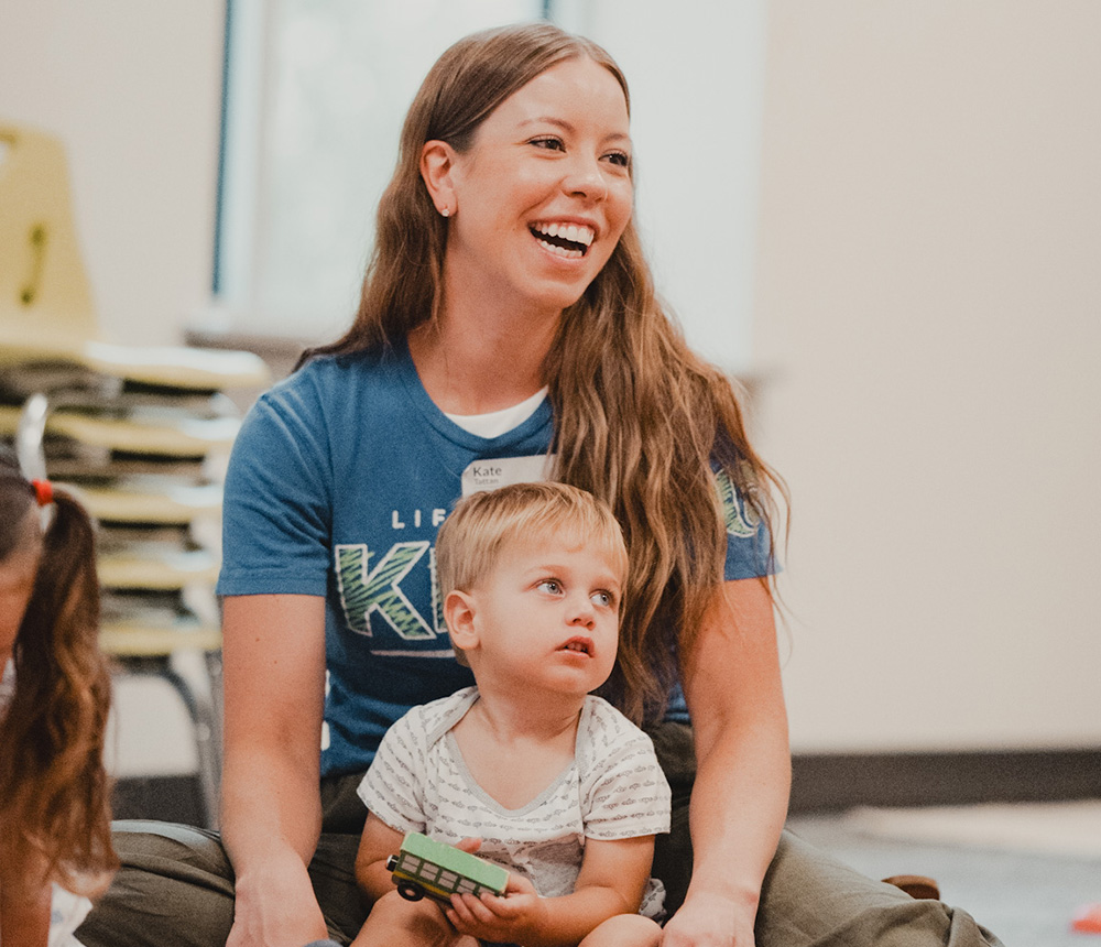 young woman smiling with preschool child on her lap