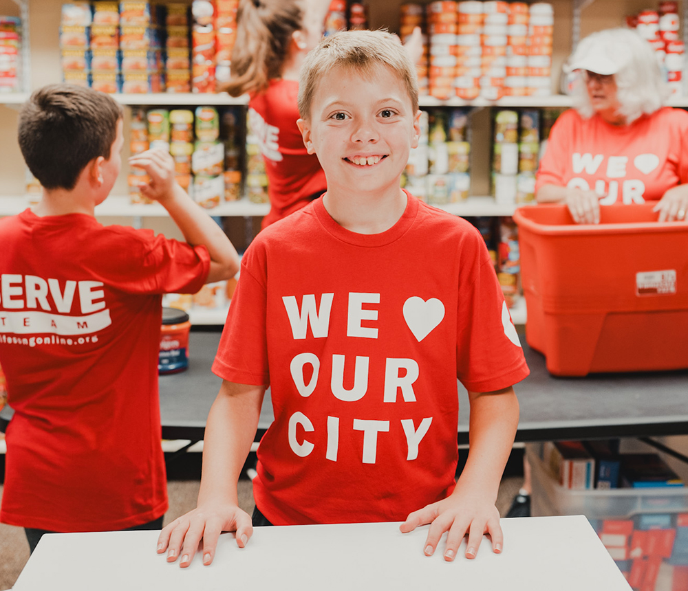 boy smiling wearing red we love our city shirt