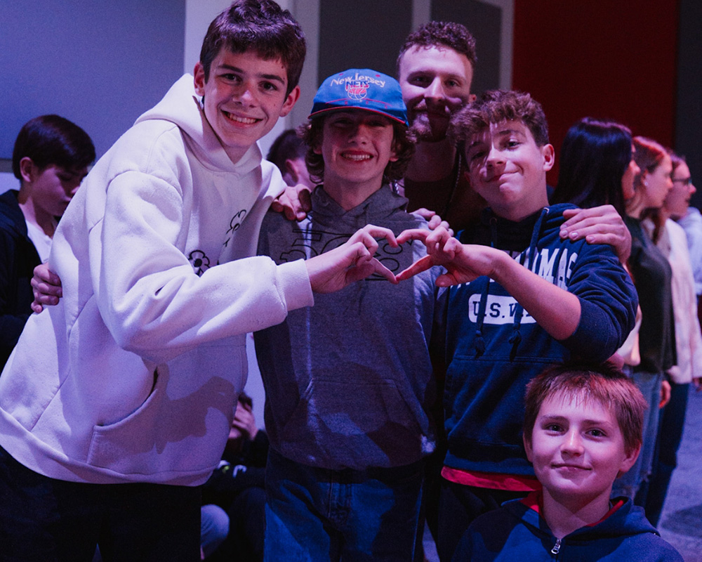 group of middle school boys smiling and making heart with hands