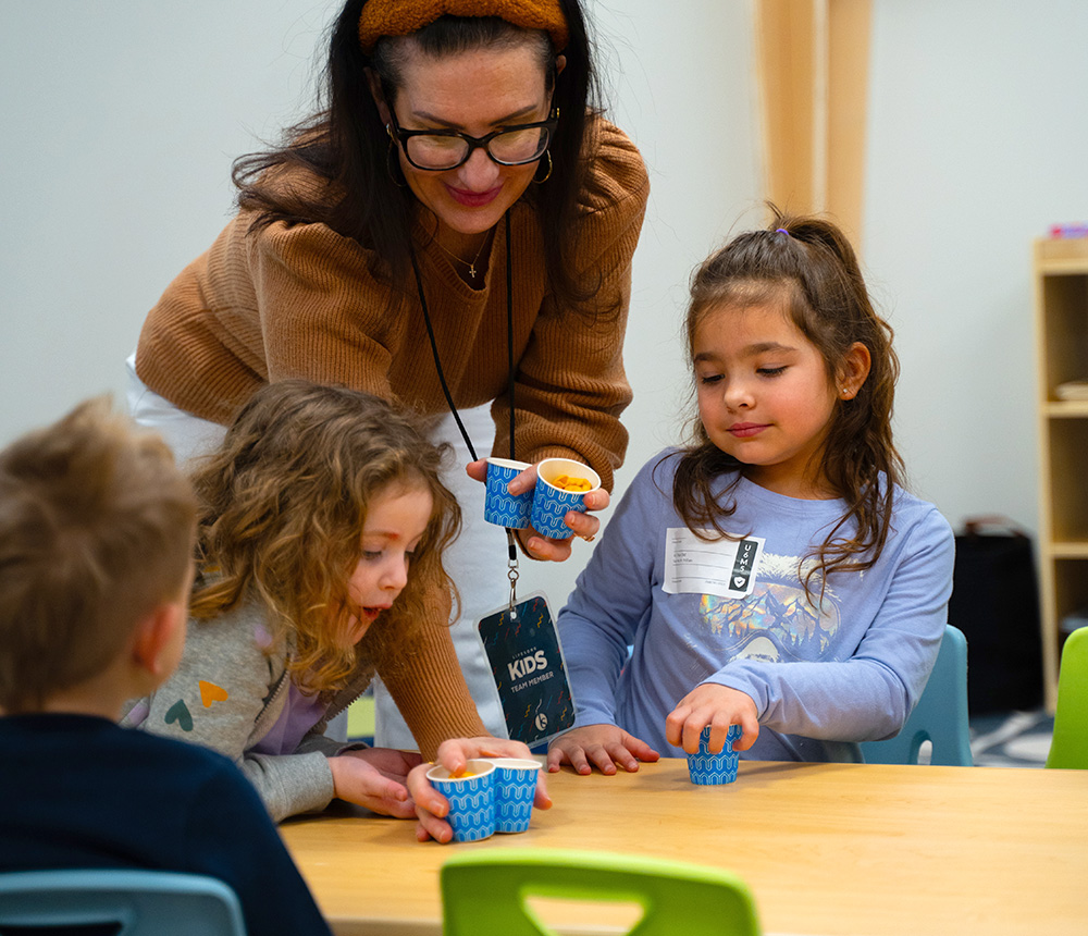 woman passing out cuts of goldfish crackers to kindergarteners