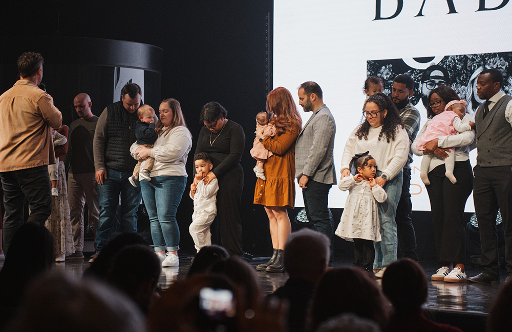 parents holding their children on platform during baby dedication